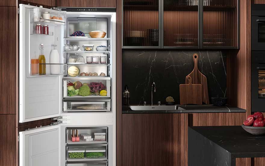 An AEG fridge, filled with fruit, vegetables, juice, and dairy, stands open in a luxury kitchen with dark wood and black marble surfaces.
