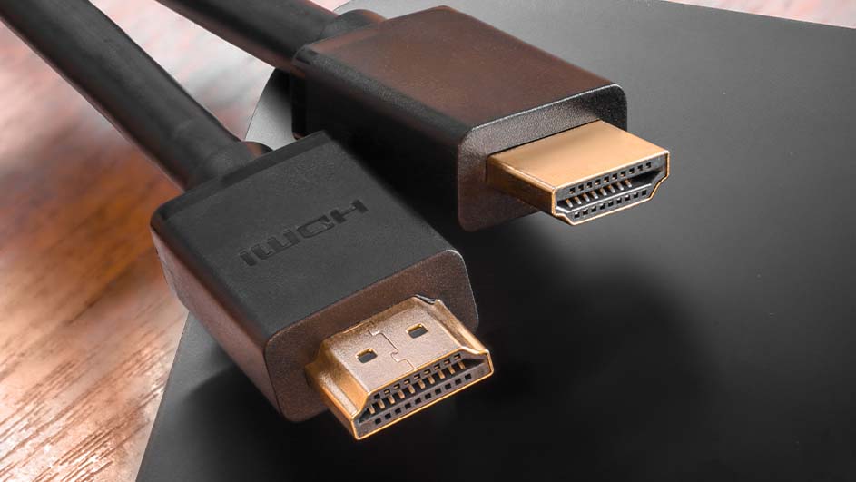 Twee zwarte HDMI-kabels met gouden connectoren liggen op een zwarte ondergrond, de achtergrond is een houten oppervlak.