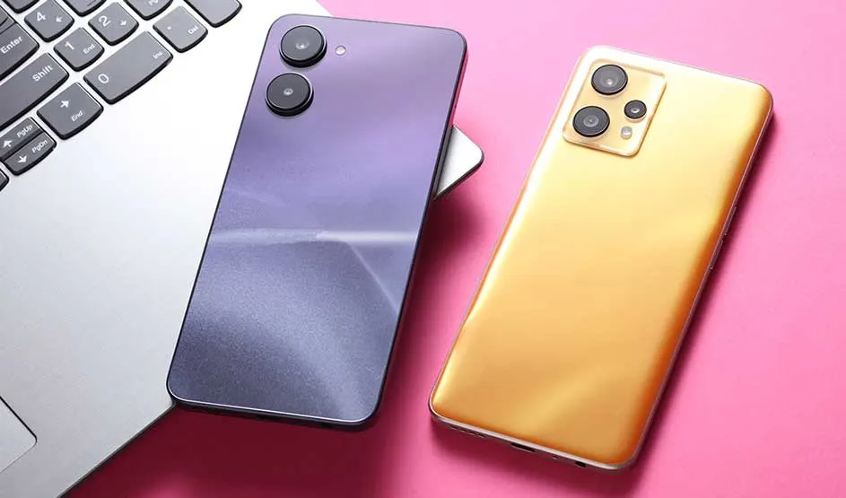 Twee Oppo smartphones, één paars en één goud, liggen naast een zilveren laptop op een roze ondergrond.