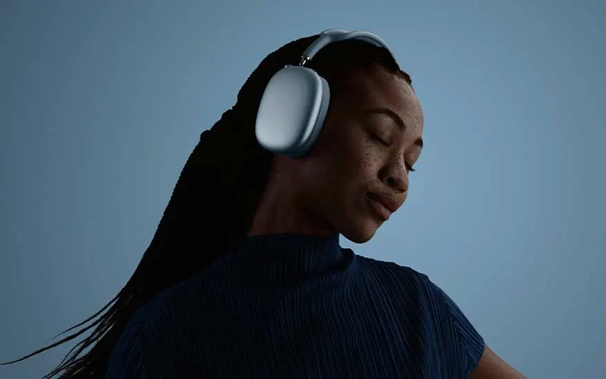 Vrouw met witte koptelefoon danst lachend buiten in een steeg, telefoon in de hand, volledig opgaand in de muziek.