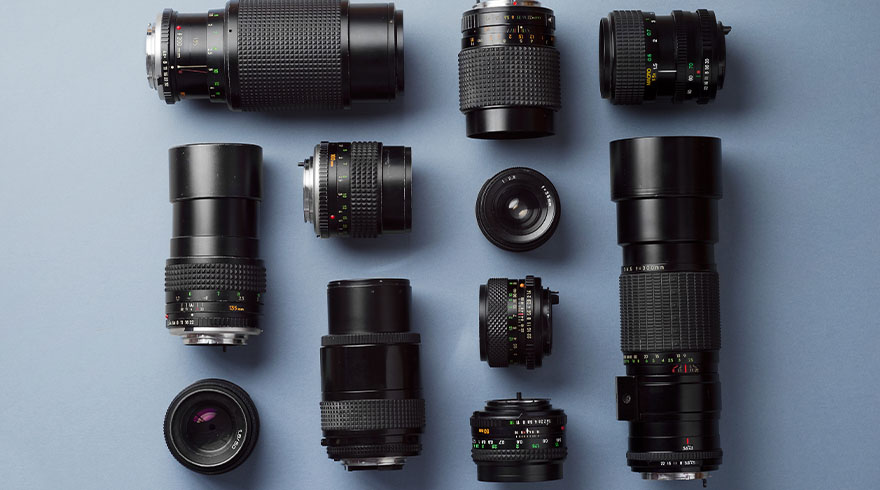 Elf zwarte cameralenzen liggen op een blauwe achtergrond, gerangschikt in een geordend patroon.