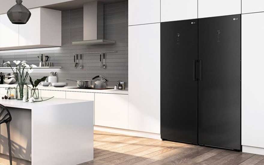 Modern white kitchen with island and wooden floor, featuring a large black side by side fridge and freezer seamlessly built into the cabinets.