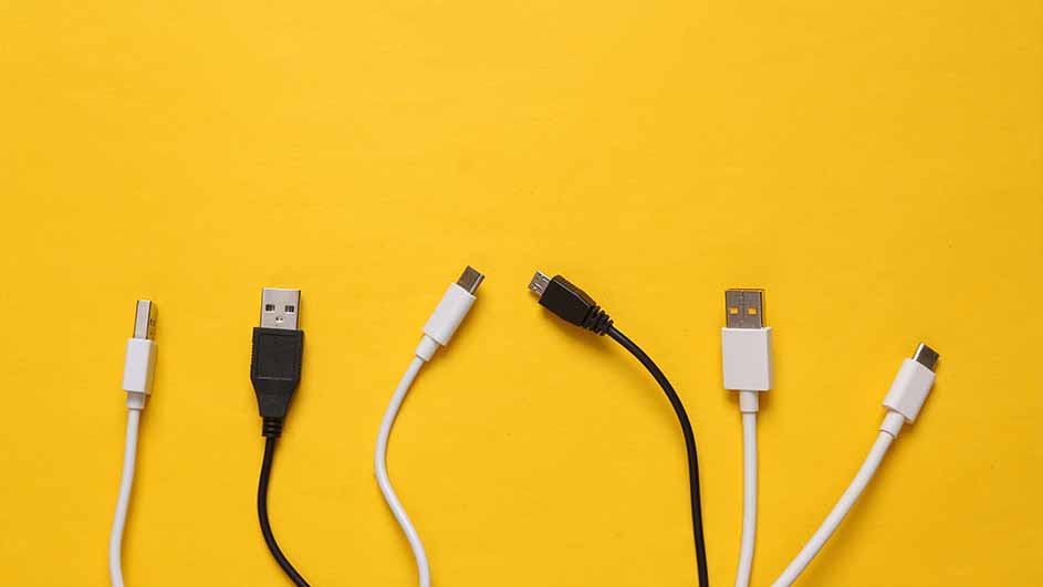 Zes USB-kabels (wit en zwart) liggen op een gele achtergrond. Verschillende soorten connectoren zijn zichtbaar.