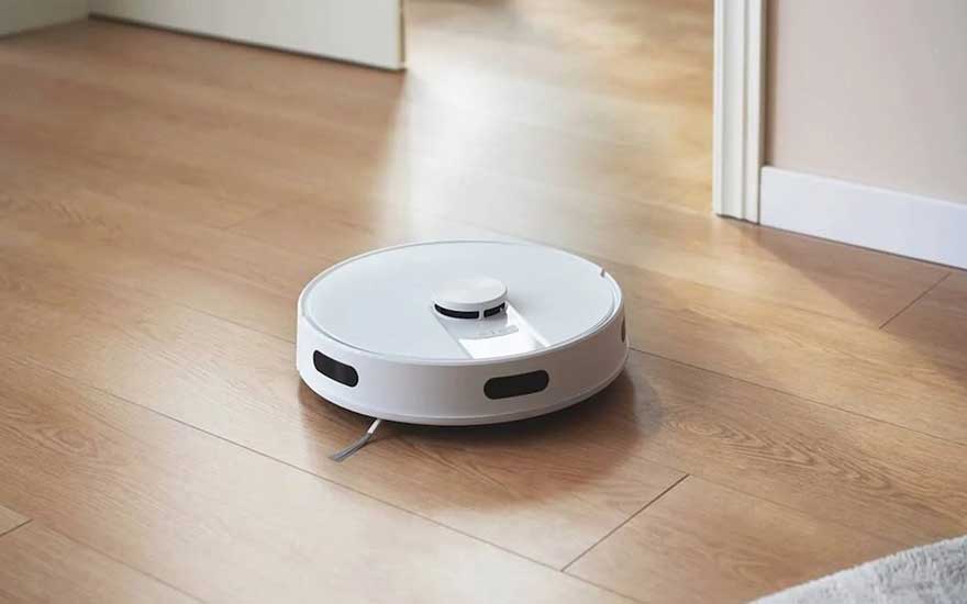 Een witte robotstofzuiger beweegt zelfstandig over een houten vloer, ideaal voor dagelijks onderhoud zonder moeite.