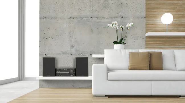 A modern living room features a white sofa, audio equipment on shelves, and a white orchid.