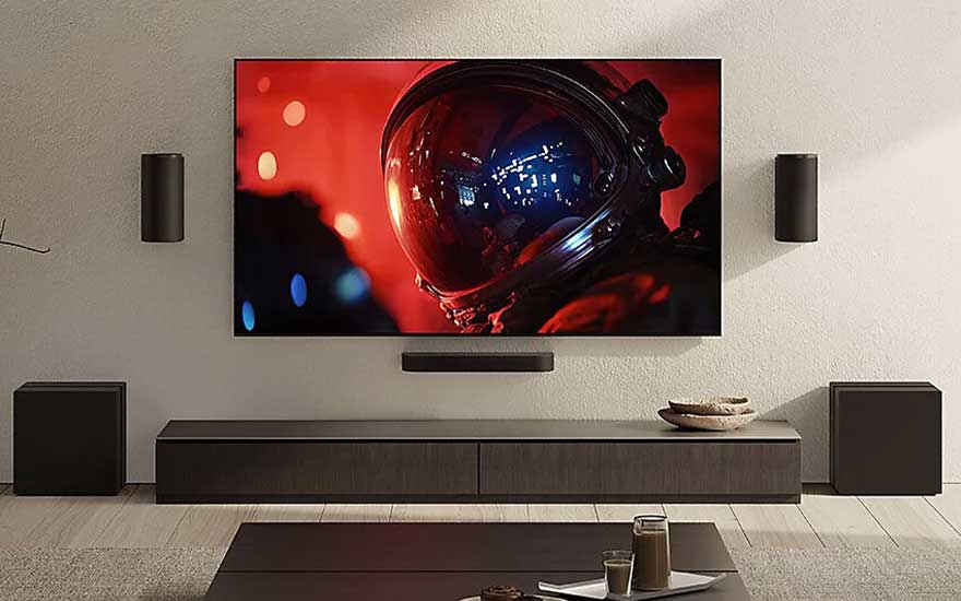 Minimalistische thuisbioscoop met grote tv, speakers en soundbar, waarop een astronautenhelm in rood licht te zien is.