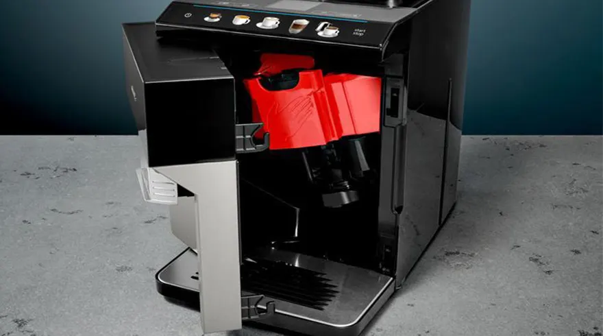 Een close-up van een koffiezetapparaat met een open zijpaneel dat een rode waterreservoir toont.