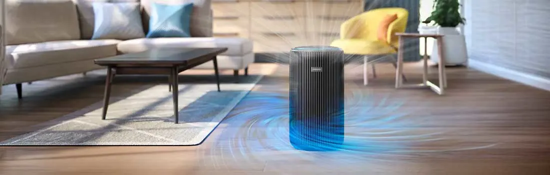 A black air purifier stands in a modern living room, sending visible streams of fresh air across the wooden floor towards the sofa and chairs.