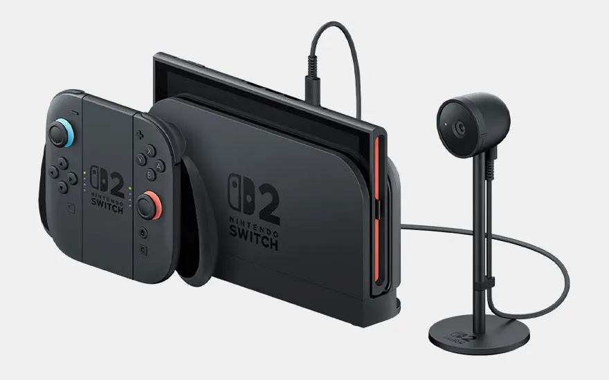 Zwarte Nintendo Switch 2 met gekleurde Joy-Con controllers aangesloten op een staande microfoon voor streaming en professionele audio-opname.