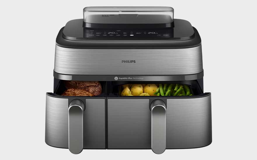Zwarte Koenic airfryer met twee lades, digitaal display en verlichte binnenkant. Kipnuggets worden bereid. Merk: Koenic.