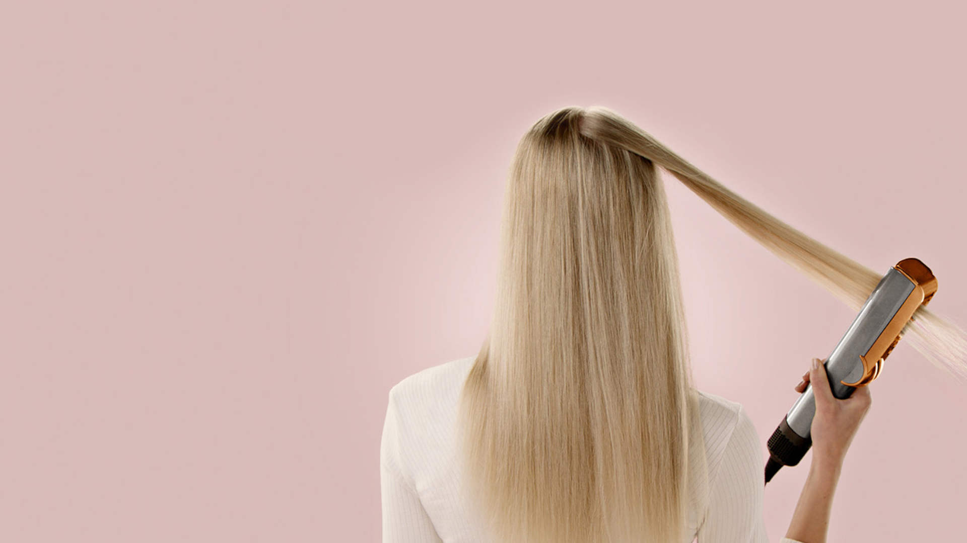 Vrouw met gestroomlijnd haar, gezien van achteren, gebruikt een stijltang tegen een effen achtergrond.