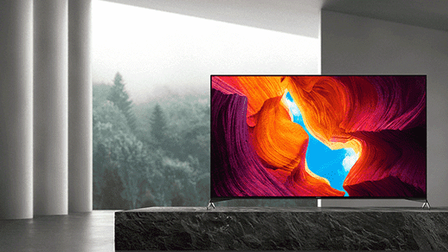 Een tv staat op een donker oppervlak, met op het scherm een abstract oranje en blauw landschap.