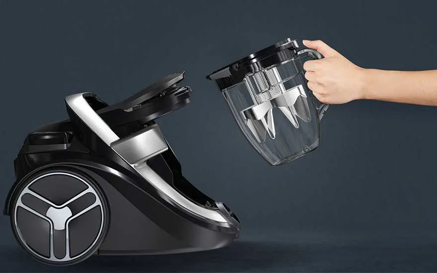 Een hand verwijdert eenvoudig het opvangreservoir van een moderne cycloonstofzuiger, klaar om geleegd te worden.