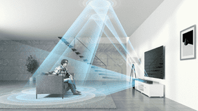 Een woonkamer met een persoon op een grijze bank, een televisie, een witte kast en blauwe lijnen voor geluid.