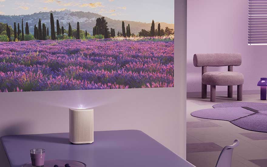 In een paars ingerichte kamer projecteert een compacte projector een lavendelveld met heuvels en bomen op de muur.