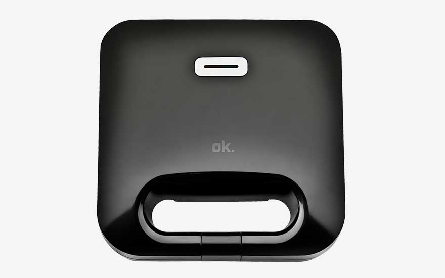 Zwart tosti-ijzer van het merk ok., minimalistisch vierkant ontwerp met geïntegreerd handvat en wit controlelampje bovenop.