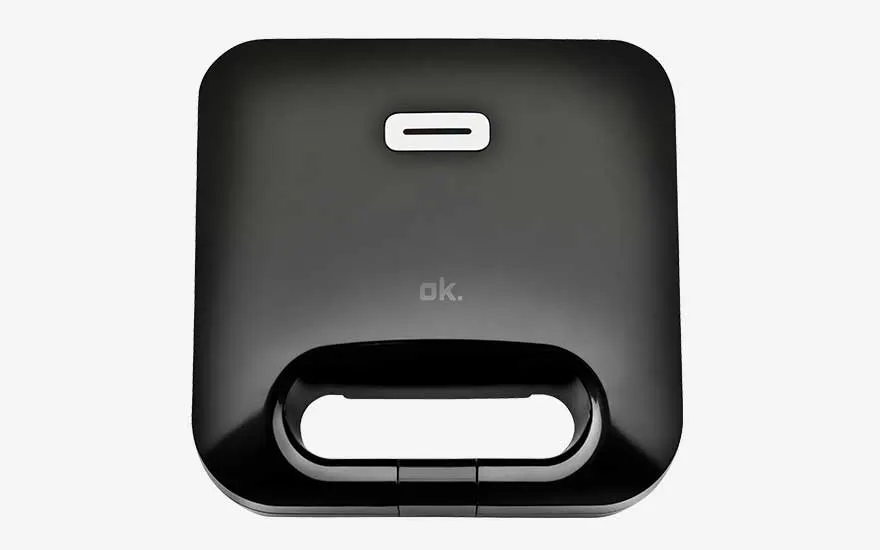 Zwart tosti-ijzer van het merk ok., minimalistisch vierkant ontwerp met geïntegreerd handvat en wit controlelampje bovenop.