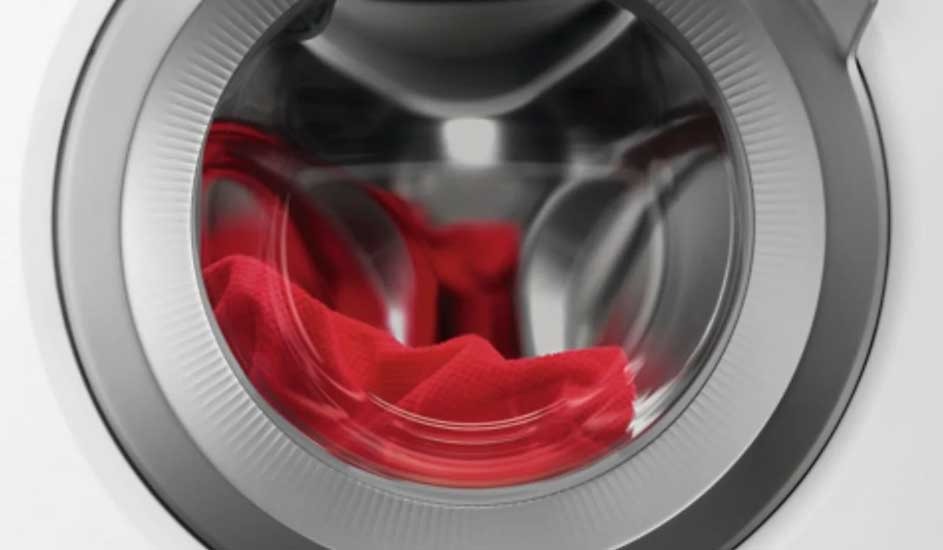 A close-up of an Electrolux washing machine door shows a red garment inside the stainless steel drum, ready for washing.