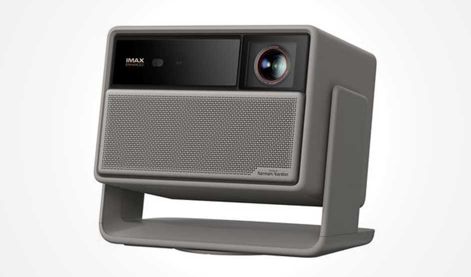 A compact grey projector with a lens and integrated stand sits against a white background.
