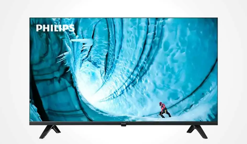 Een Philips tv met slanke rand toont een heldere afbeelding van een klimmer in een blauwe ijsgrot, met het Philips-logo linksboven.