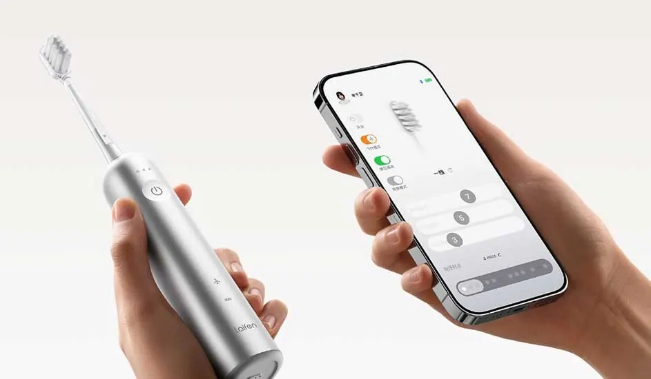 Een zilveren elektrische tandenborstel van het merk Aifen wordt vastgehouden naast een smartphone waarop een bijbehorende app geopend is.