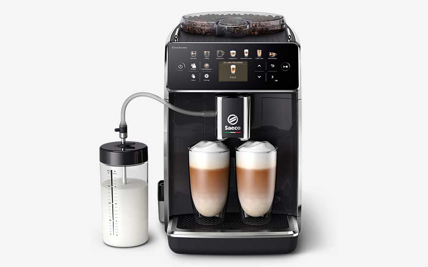 A black Saeco coffee machine with a touchscreen, two glasses of latte macchiato and a milk container next to it.