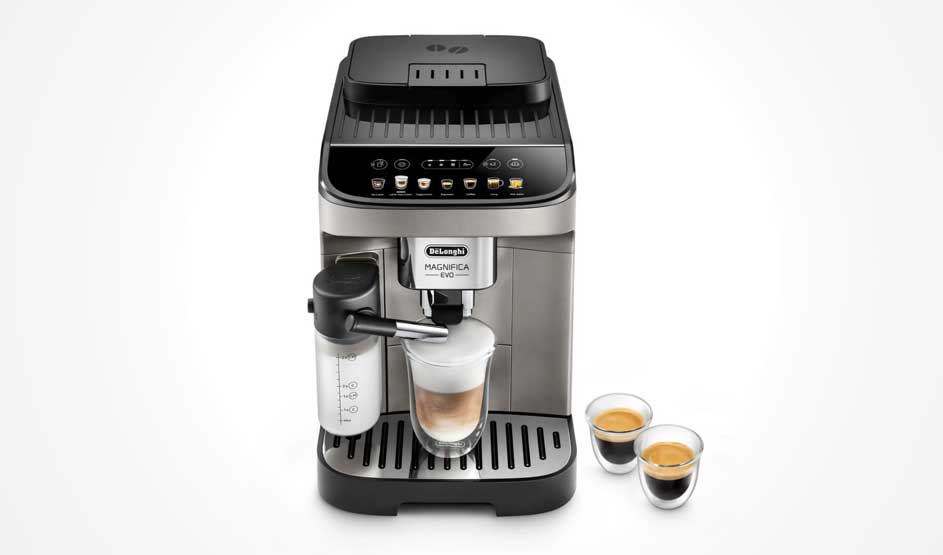 Een DeLonghi koffiemachine maakt een cappuccino in een glas, met melkreservoir links en twee kleine espresso’s ernaast op tafel.
