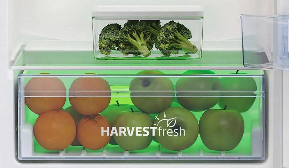 In de koelkast liggen oranje sinaasappels en groene appels in een lade met HARVESTfresh erop, daarboven een bakje met verse broccoli.