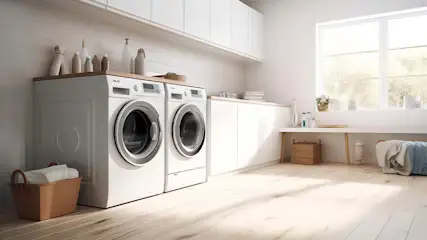 Een lichte wasruimte met twee witte wasmachines, een houten vloer en opbergmanden. Bovenkasten en een groot raam zorgen voor helderheid.