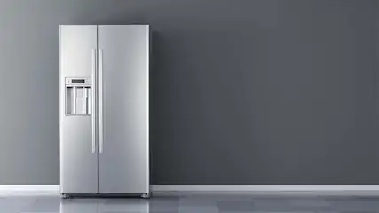 A stainless steel refrigerator with dispenser stands against a gray wall and floor.