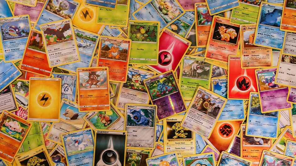 Pile of Pokémon cards scattered, showing various characters, energy symbols, and card designs with yellow borders.