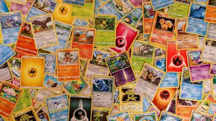 Pile of Pokémon cards scattered, showing various characters, energy symbols, and card designs with yellow borders.