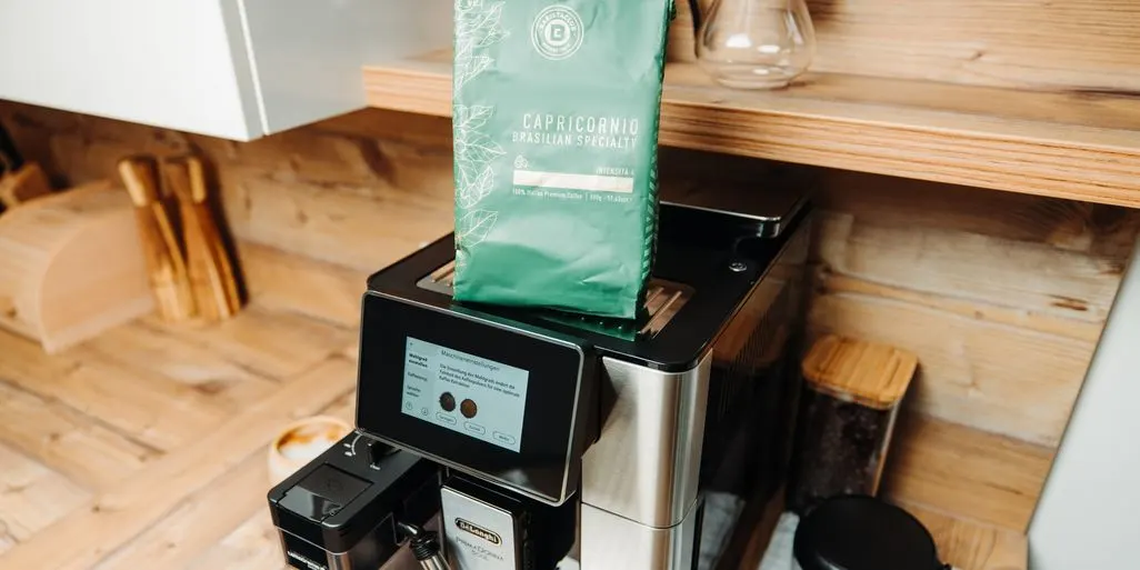 DeLonghi Kaffeevollautomat mit grossem Display in Kueche, darauf steht eine Packung Kaffee