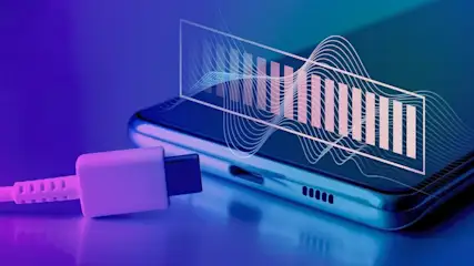 USB-C-Ladekabel liegt vor einem Smartphone mit grafischem Akku Symbol auf lila blauem Hintergrund.