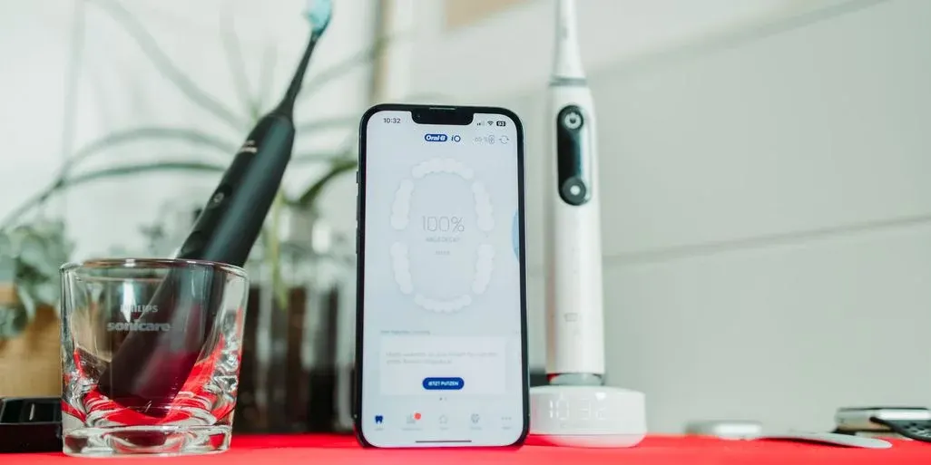 Smartphone mit geoeffneter Oral B App zwischen 2 Zahnbuersten