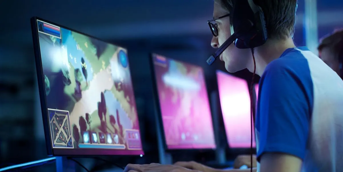 Person mit Headset spielt an mehreren Monitoren ein Computerspiel