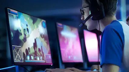 Person mit Headset spielt an mehreren Monitoren ein Computerspiel