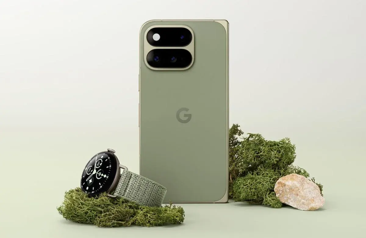 Google Pixel Smartphone in Olivgrün mit markanter Doppelkamera-Leiste, daneben eine Pixel Watch mit Textilarmband auf Moos-Dekoration.
