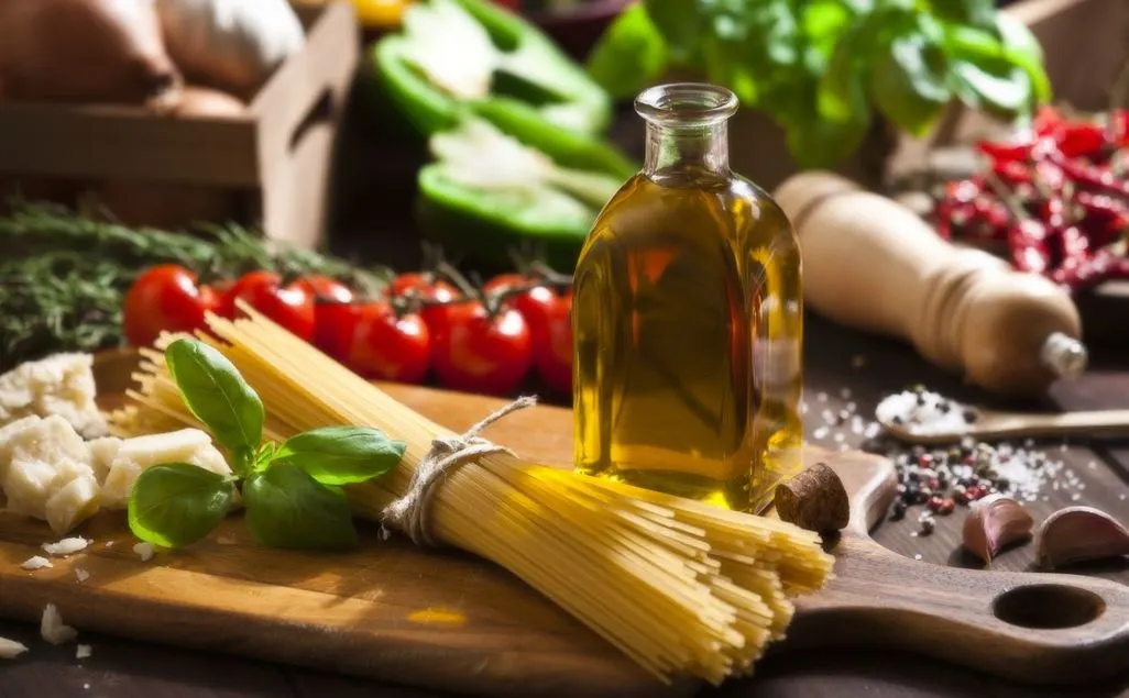 Spaghetti-Bund, Olivenölflasche, Parmesan, Tomaten, Basilikum, Knoblauch, Salz und Pfeffer auf Holzbrett.