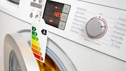 Eingeschaltete Waschmaschine mit 1:27h Restlaufzeit, ein Energieeffizienzlabel der Klasse A hängt am Drehknopf.