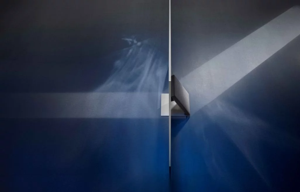 Fernseher mit einem sehr dünnen Bildschirm, der an einer blauen Wand montiert ist, mit Lichteffekten auf beiden Seiten.