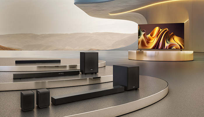Mehrere schwarze Hisense‑Soundbars und Subwoofer vor Fernseher in modernem Showroom.