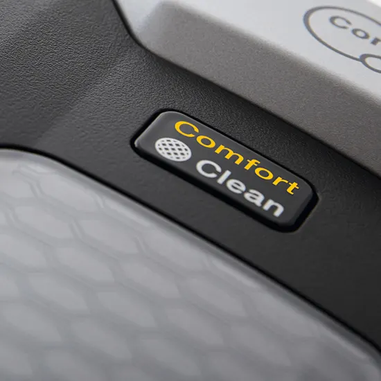 Nahaufnahme eines schwarzen Knopfes mit goldener Schrift "Comfort Clean" auf einem grauen Gerät.