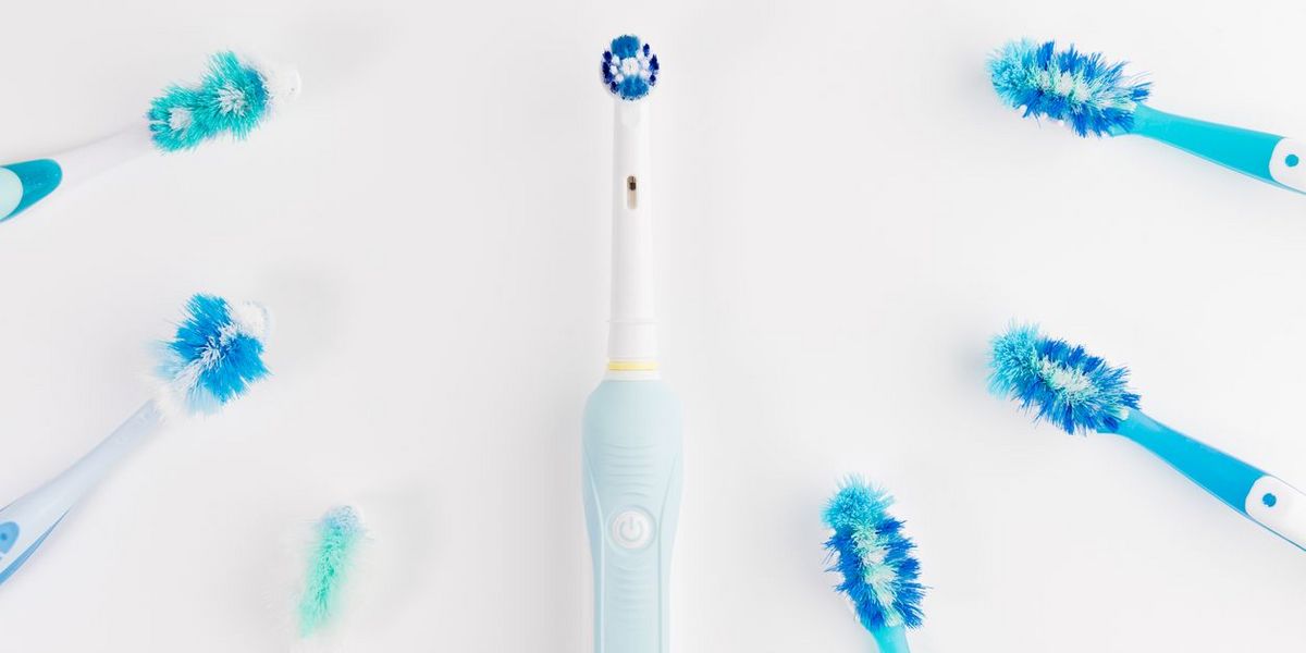 Elektrische Zahnbürste in der Mitte, umgeben von mehreren abgenutzten Zahnbürsten.