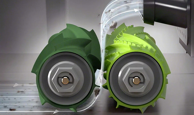 Zwei grüne, zahnradartige Walzen mit grauen Naben stehen sich gegenüber, während ein Abzugsstutzen oben rechts Schmutz absaugt.