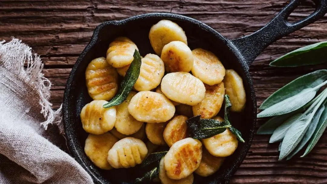 Frisch gebratene Gnocchi mit Salbeiblättern in einer kleinen Pfanne.