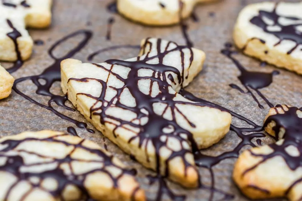 Mürbeteigkekse mit dunkler Schokolade verziert auf Backpapier.