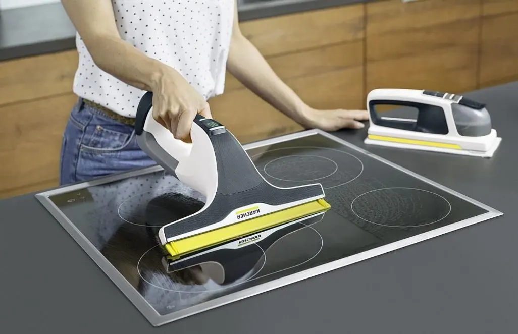 Person reinigt ein Cerankochfeld mit einem Fenstersauger