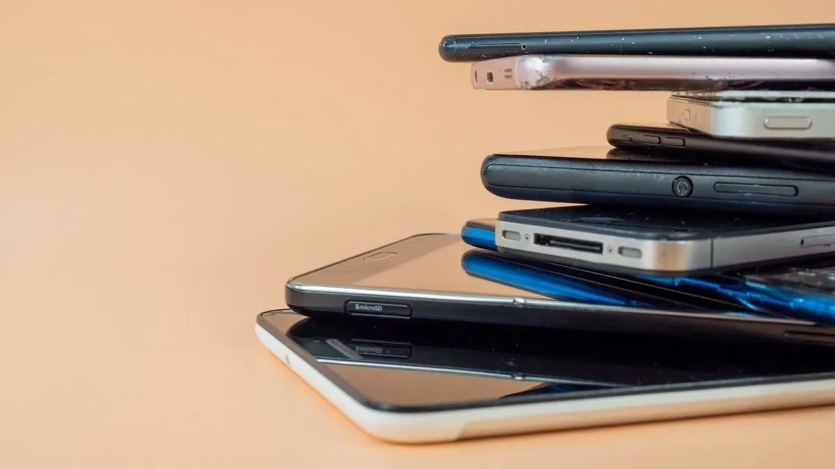 Ein Stapel verschiedener alter teils beschädigter Smartphones.