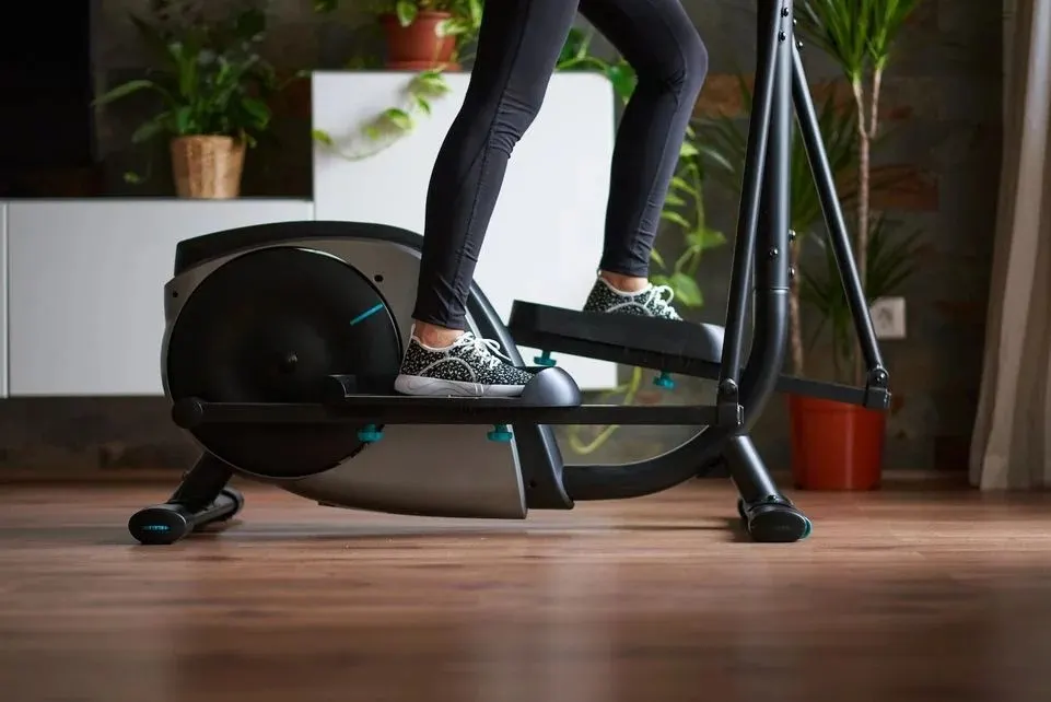 Nahaufnahme von Beinen einer Frau, die auf einem Crosstrainer trainiert.